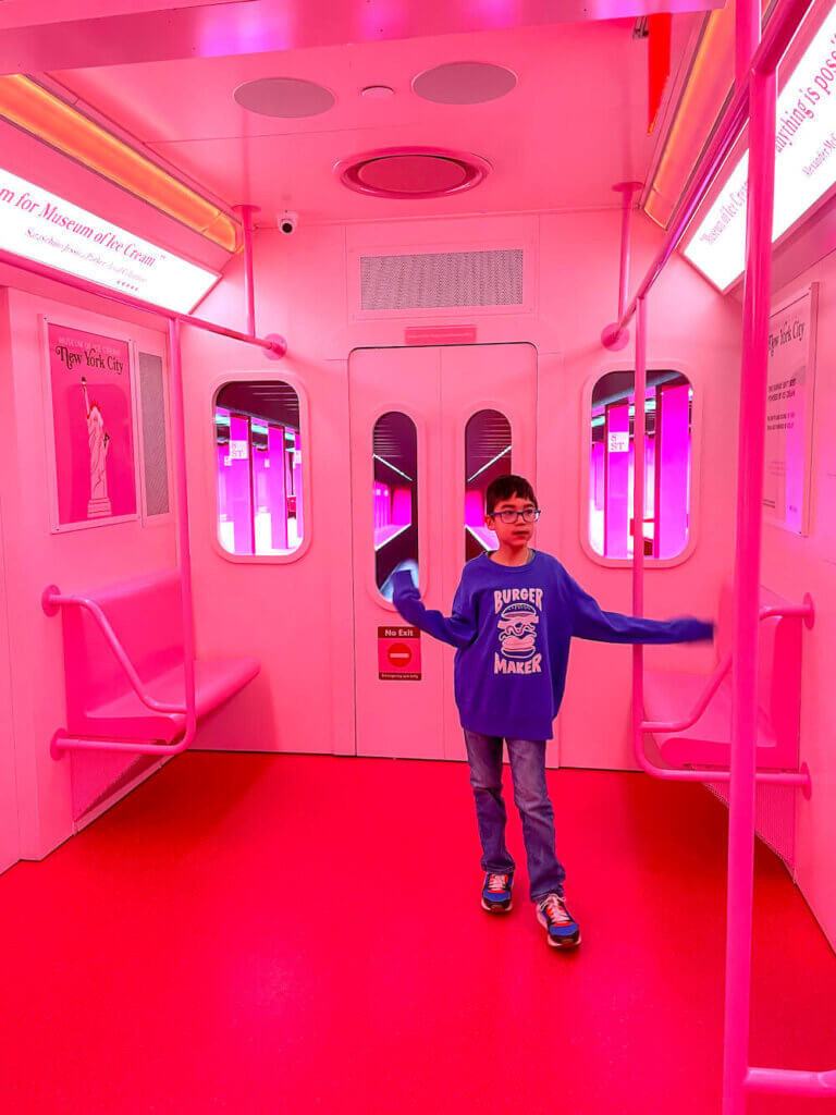 Image of a boy standing in a pink subway car
