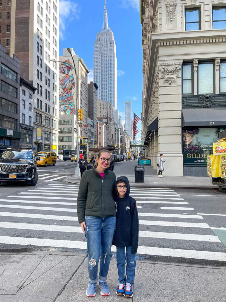Image of a mom and son posing on a NYC street with the Empire State Building in the background