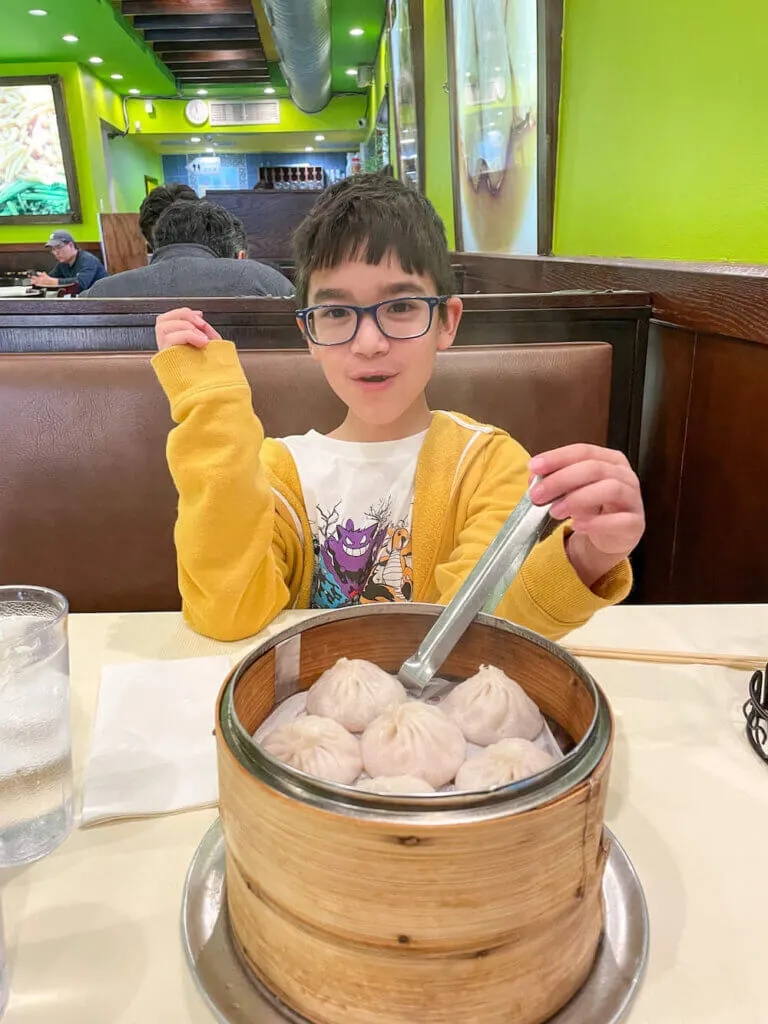 Image of a boy with a tray of soup dumplings