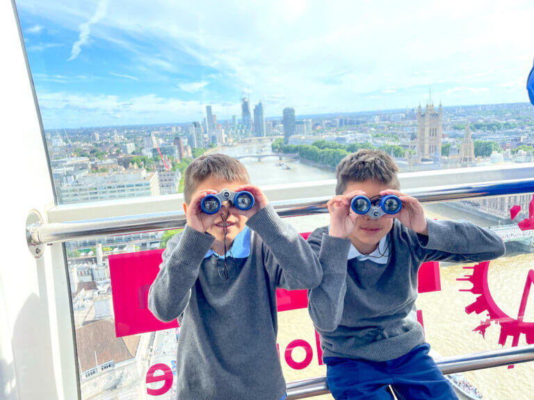 Find out how to spend 4 days in London with kids by top family travel blog Marcie in Mommyland. Image of two boys using binoculars on the London Eye