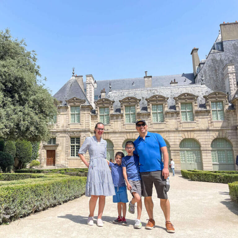 Find out how to spend 5 days in Paris with kids by top family travel blog Marcie in Mommyland. Image of a family posing in front of an old building in Paris France
