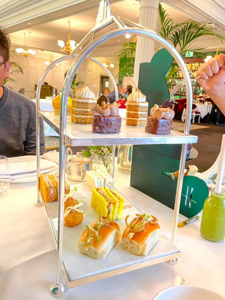 Image of a two-tiered tray filled with finger sandwiches and bite-sized desserts at Harrods in London