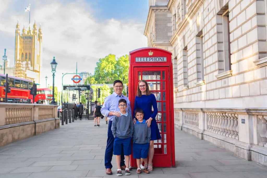 Image of a family of four posing in front of a red phone booth on a street in London