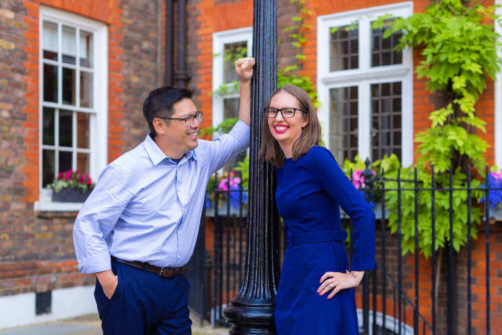 Image of a man leaning on a street lamp looking at a woman in a blue dress on a London photo shoot
