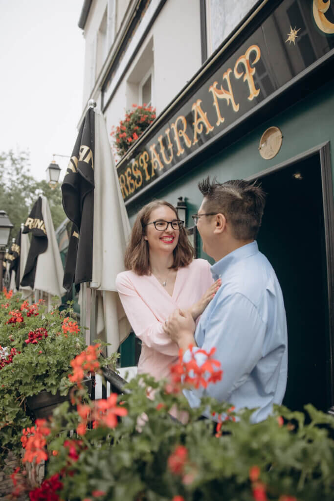 Image of a man and woman posing behind some flowers at a cafe in Paris