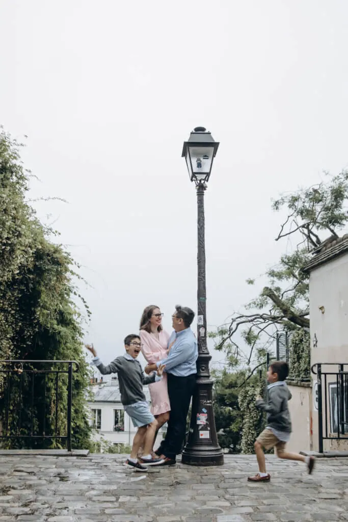 Image of a couple leaning against a streetlight while their boys run around acting crazy for a Paris photo shoot.