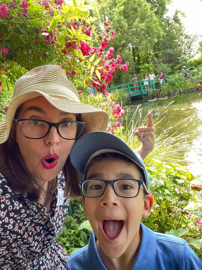 Find out what to do in Giverny with kids by top family travel blog Marcie in Mommyland. Image of a mom and son at Monet's garden with a green bridge in the background