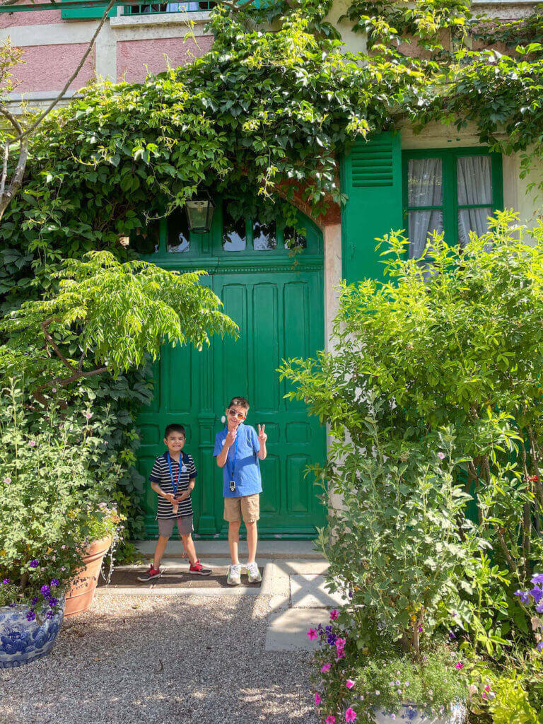 Image of two boys standing in front of green doors at Claude Monet's house in Giverny France