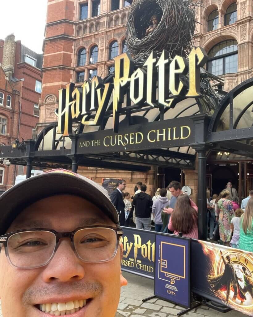 Image of a man taking a selfie in front of the Harry Potter and the Cursed Child sign