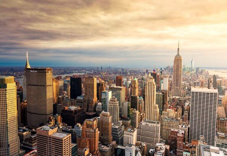 Find out how to save money in New York City by top family travel blog Marcie in Mommyland. Image of a NYC cityscape at sunset