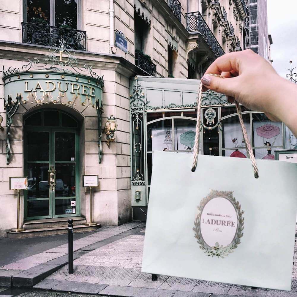 Image of a Laduree bag in front of the Laduree shop in Paris
