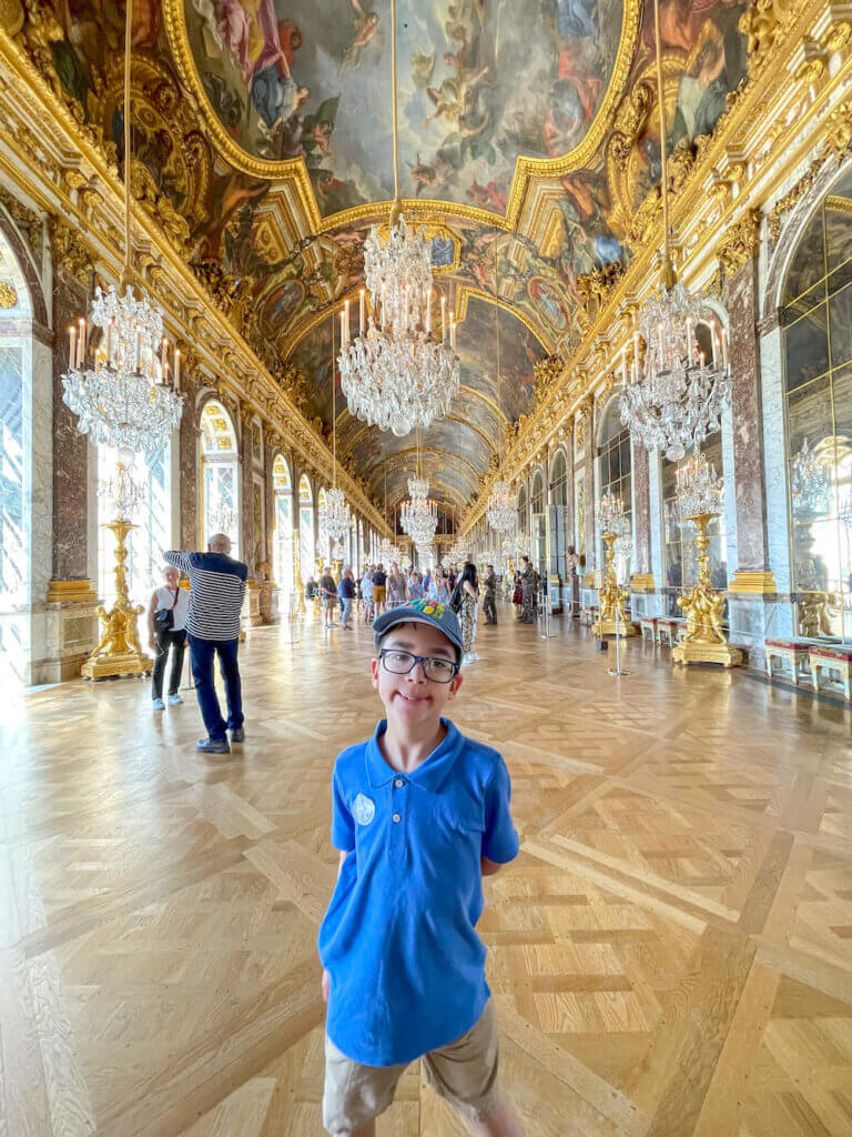 Image of a boy standing in the Hall of Mirrors at Versailles in France