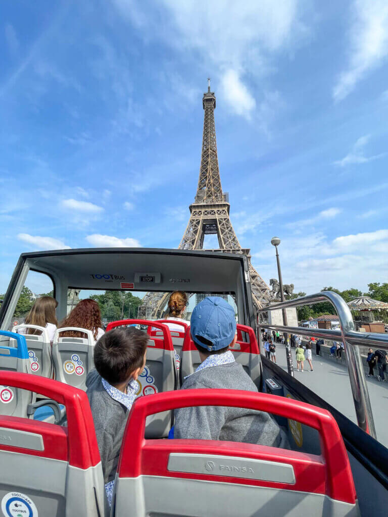 Image of two boys on a double decker bus in front of the Eiffel Tower