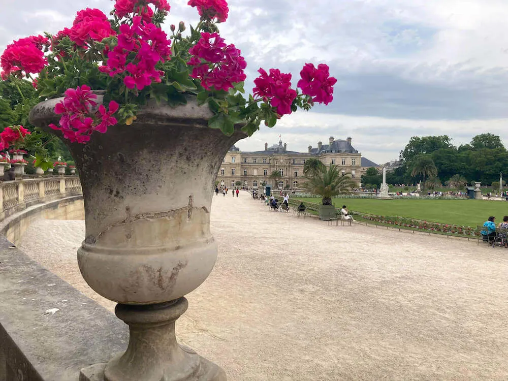 Image of a pot of pink flowers in front of an old French building at the Tuilleries Garden in Paris
