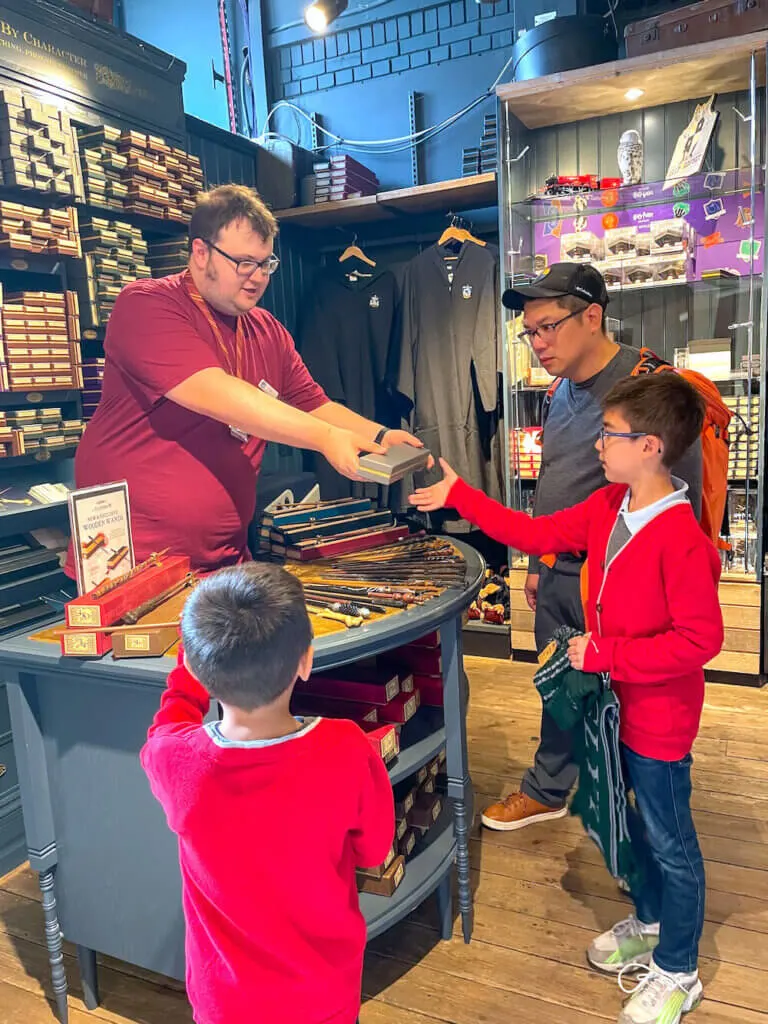 Image of two boys in red sweaters receiving wands at the Harry Potter store at King's Cross Station in London.