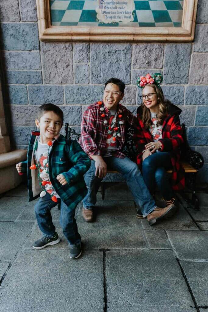 How to Book a Fun-Filled Disneyland Photography Session: Image of a couple sitting on a bench while a boy dances in front.