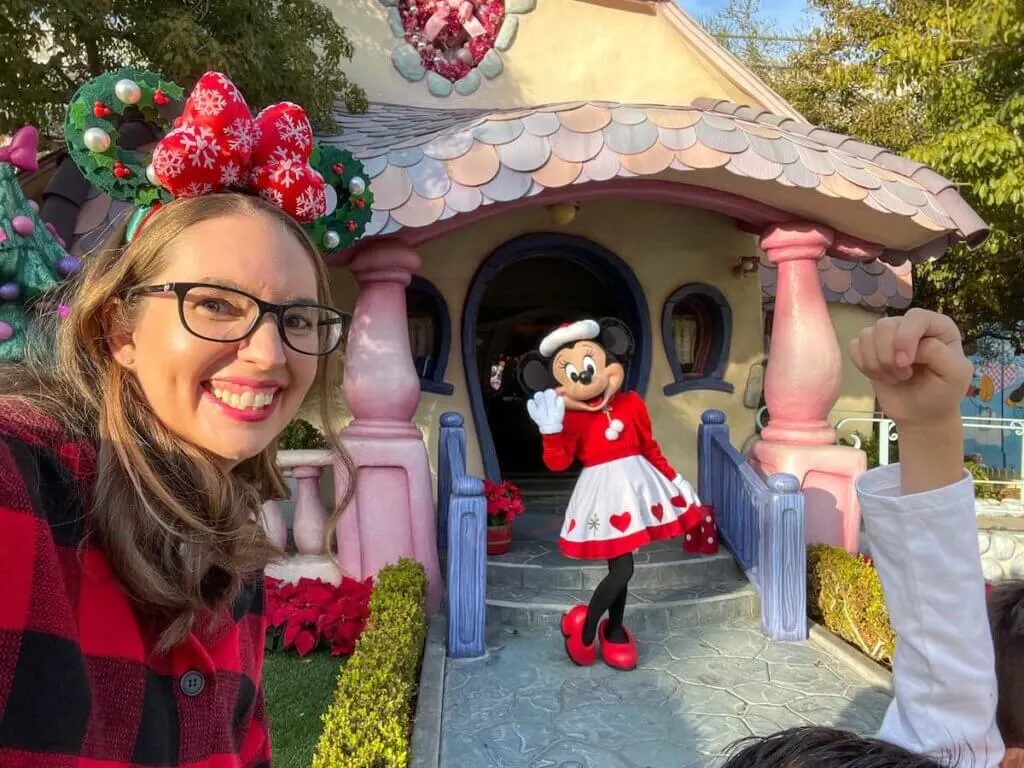 Find out the best Disneyland Christmas activities to do this year recommended by top family travel blog Marcie in Mommyland. Image of a mom wearing Minnie ears with Minnie Mouse in the background