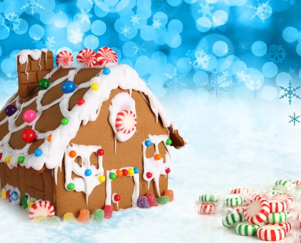 Making a gingerbread house should be on your Christmas bucket list! Image of Gingerbread house on a festive Christmas snow background.