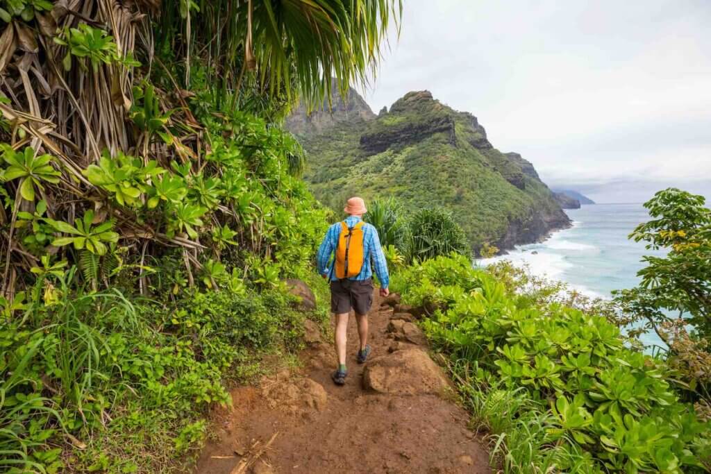 Kauai is one of the top warm vacation spots in the U.S. Image of Hiker on the trail in green jungle, Hawaii, USA
