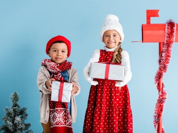 Check out the best Secret Santa gift ideas for kids recommended by top family blog Marcie in Mommyland. Image of festive-looking kids holding presents