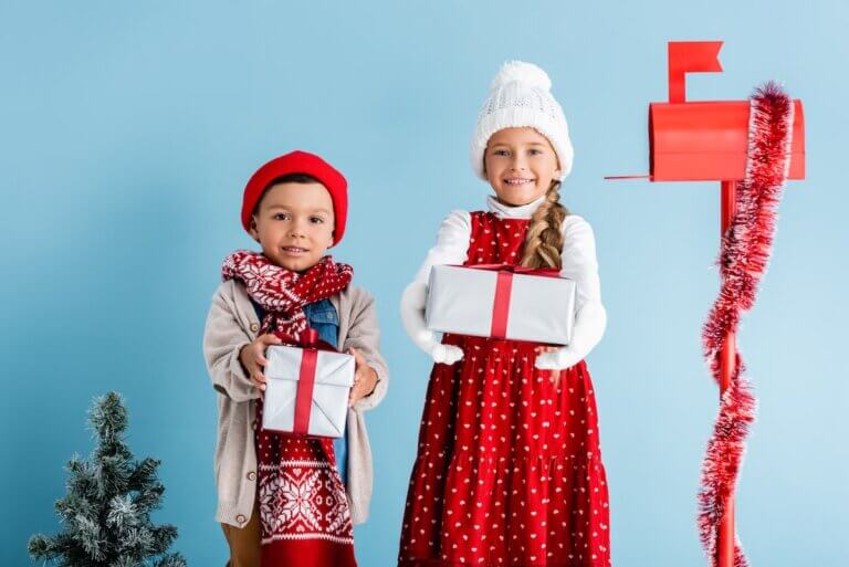 Check out the best Secret Santa gift ideas for kids recommended by top family blog Marcie in Mommyland. Image of festive-looking kids holding presents