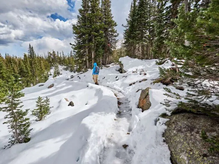 Find out the best places for winter hiking in the USA. Image of Tourist with backpack hiking on snowy trail in Rocky Mountain National Park, Colorado, USA.