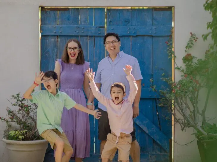 Find out how to book the best Cabo family photos according to top family travel blog Marcie in Mommyland. Image of a family acting silly in front of a blue door in Cabo San Lucas Mexico