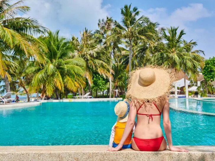 Debating Hawaii vs Mexico for your next family vacation? Check out this honest comparison by top family travel blog Marcie in Mommyland. Image of Three year old toddler boy in resort swimming pool with mother.