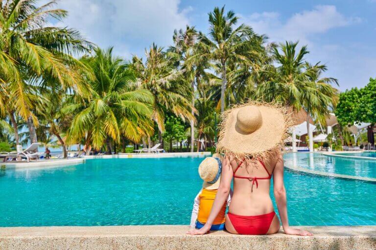 Debating Hawaii vs Mexico for your next family vacation? Check out this honest comparison by top family travel blog Marcie in Mommyland. Image of Three year old toddler boy in resort swimming pool with mother.