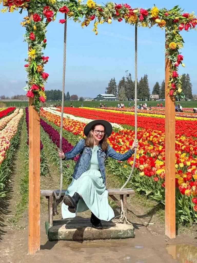 Image of a woman sitting in a giant swing at Tulip Town at the Skagit Valley Tulip Festival
