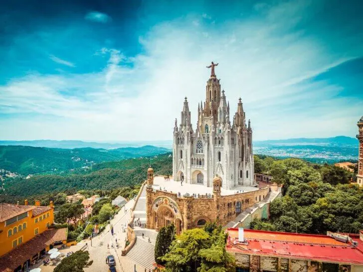 Check out these Barcelona travel tips for Spain by top travel blog Marcie in Mommyland. Image of Tibidabo church on mountain in Barcelona with christ statue overviewing the city