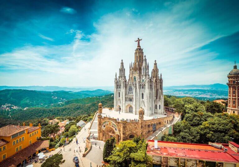 Check out these Barcelona travel tips for Spain by top travel blog Marcie in Mommyland. Image of Tibidabo church on mountain in Barcelona with christ statue overviewing the city