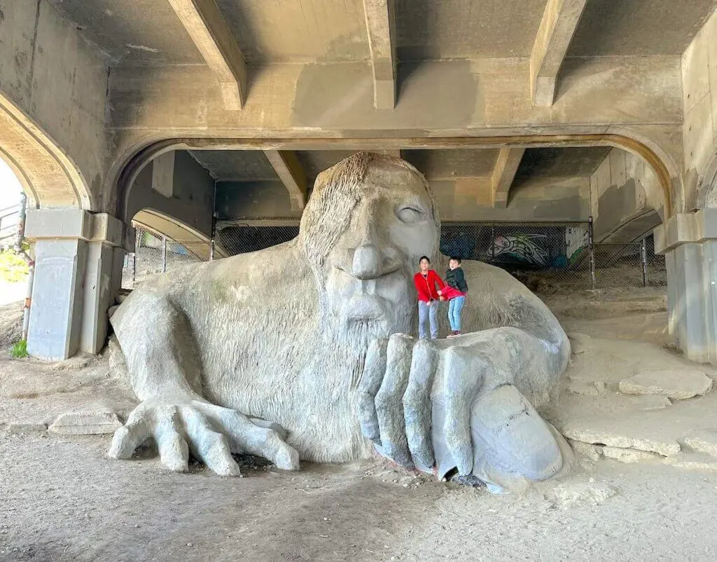 Image of two kids standing on the Fremont Troll in Seattle