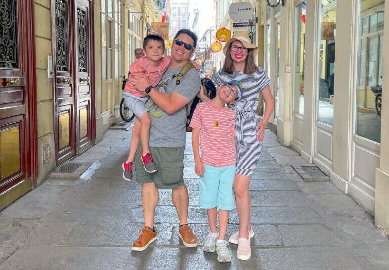 Check out this comparison of Paris vs London by top family travel blog Marcie in Mommyland. Image of a family posing inside an alley in Paris