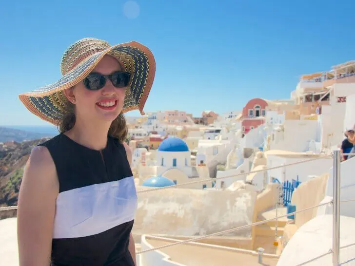 Check out these essential travel tips for Santorini Greece by top family travel blog Marcie in Mommyland. Image of a woman posing in Oia on Santorini Greece