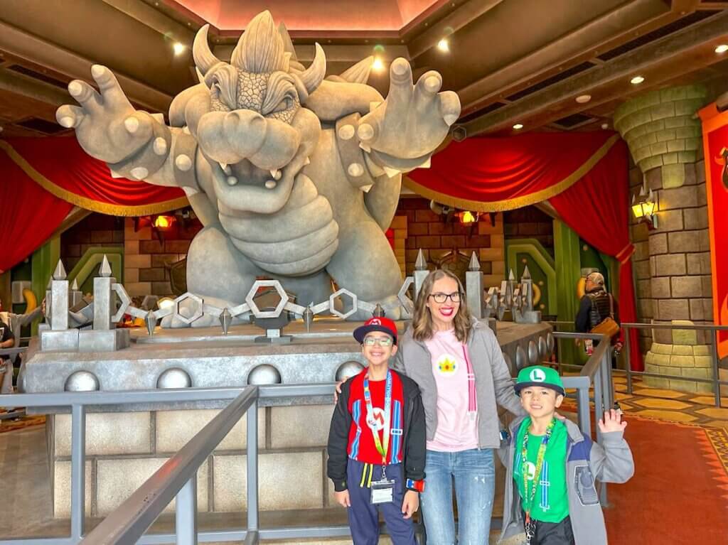 Image of a mom and two boys in front of a Bowser statue at Super Nintendo World
