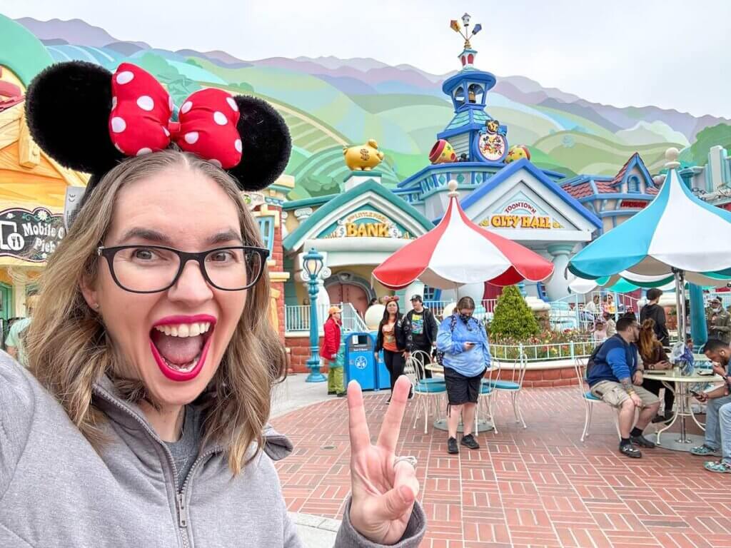Get the top tips and tricks for visiting Disneyland Toontown by top family travel blog Marcie in Mommyland. Image of a woman taking a selfie at Mickey's Toontown in Disneyland California.