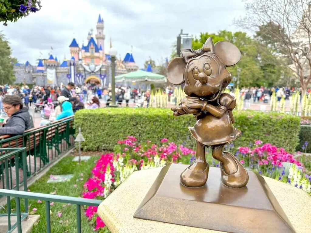 Image of a small Minnie Mouse statue at Disneyland with the castle in the background