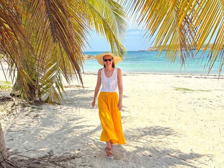 Check out these amazing Puerto Rico travel tips by top family travel blog Marcie in Mommyland. Image of a woman wearing a yellow skirt on a beach in Vieques Puerto Rico