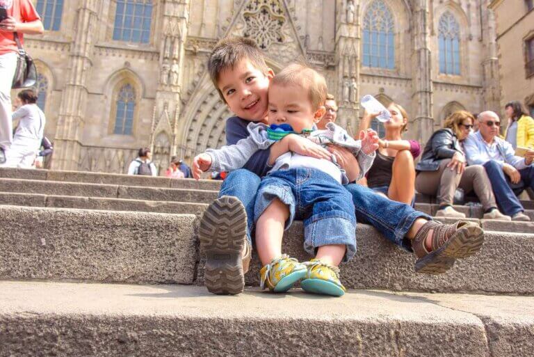 Find out the coolest things to do in Barcelona with kids recommended by top family travel blog Marcie in Mommyland. Image of a baby and a toddler sitting on the steps of Sagrada Familia