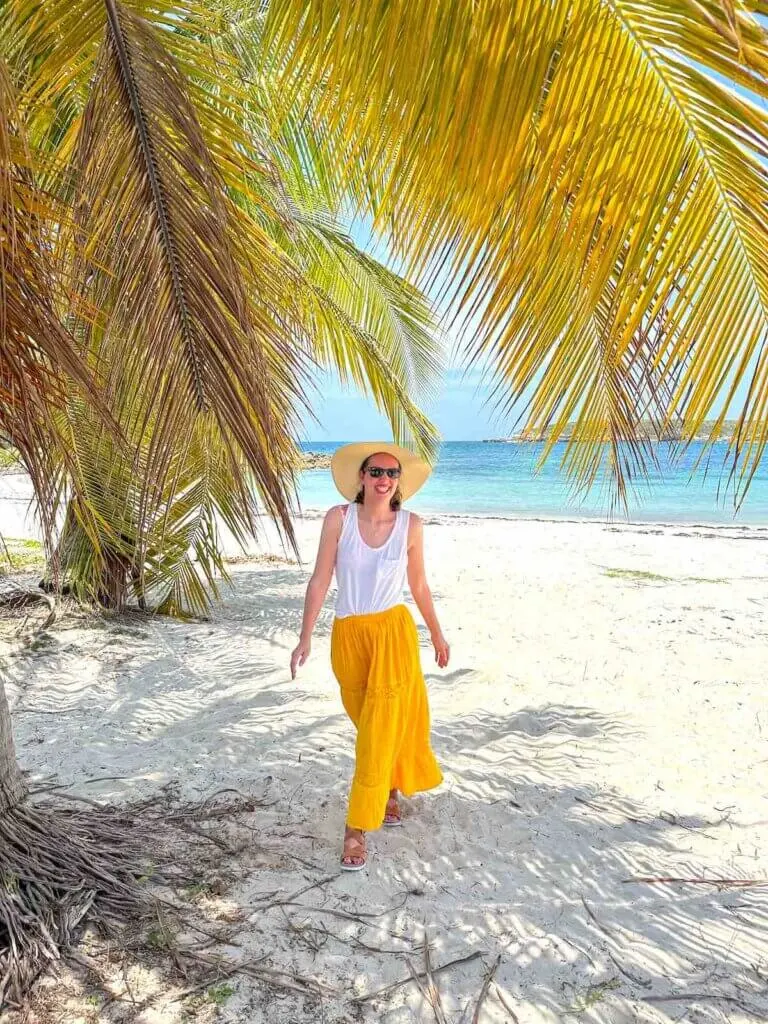 Image of a woman walking on a beach in Vieques under a palm tree