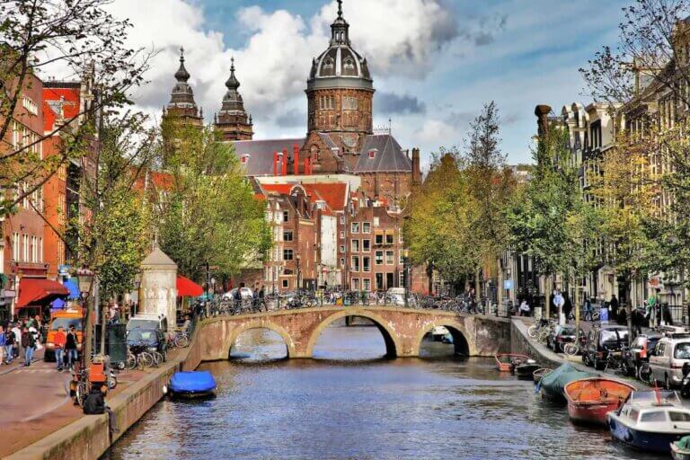 Check out the best Amsterdam hotels for families recommended by top family travel blog Marcie in Mommyland. Image of a canal in Amsterdam