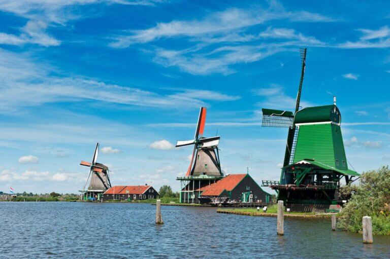 Check out this list of the best day trips from Amsterdam by train recommended by top family travel blog Marcie in Mommyland. Image of Windmill landscape in the Zaanse Schans, the Netherlands