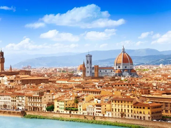 Check out this list of the best Florence hotels for families visiting Italy with kids recommended by top family travel blog Marcie in Mommyland. Image of Cityscape panorama of Arno river, towers and cathedrals of Florence