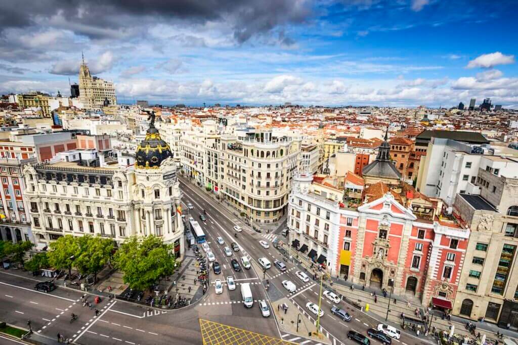 Check out these best Madrid hotels for families visiting Spain with kids recommended by top family travel blog Marcie in Mommyland. Image of Madrid, Spain cityscape above Gran Via shopping street.