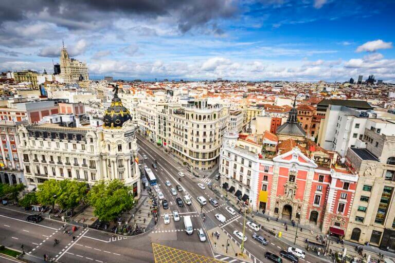 Check out these best Madrid hotels for families visiting Spain with kids recommended by top family travel blog Marcie in Mommyland. Image of Madrid, Spain cityscape above Gran Via shopping street.