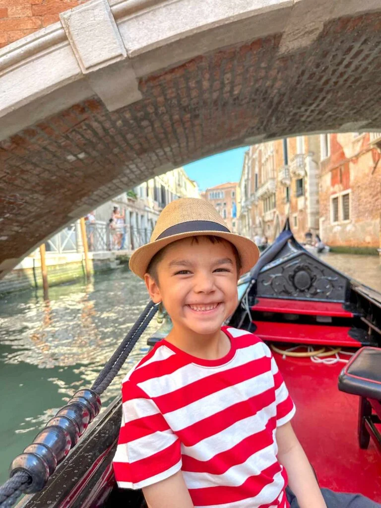 Image of a boy dressed as a gondolier in a gondola in Venice Italy