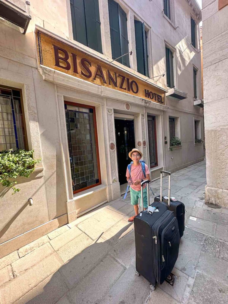 Image of a boy with suitcases in front of the Hotel Bisanzio in Venice Italy
