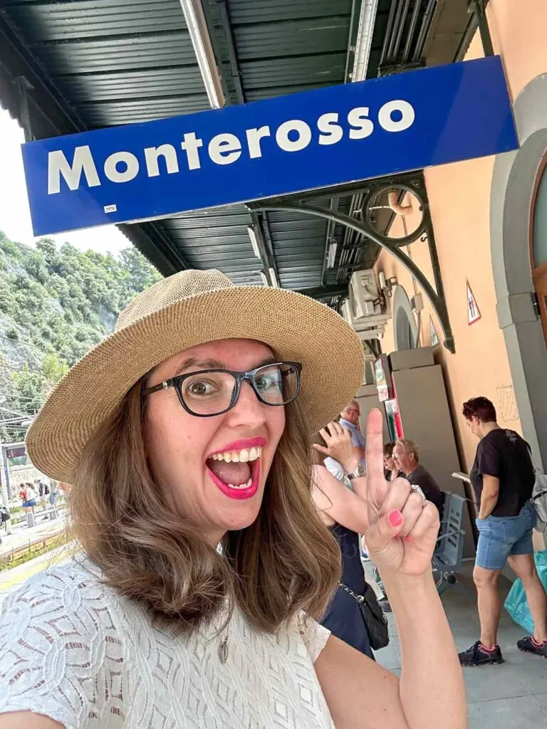 Image of a woman in front of the Monterosso sign at the train station in Cinque Terre Italy