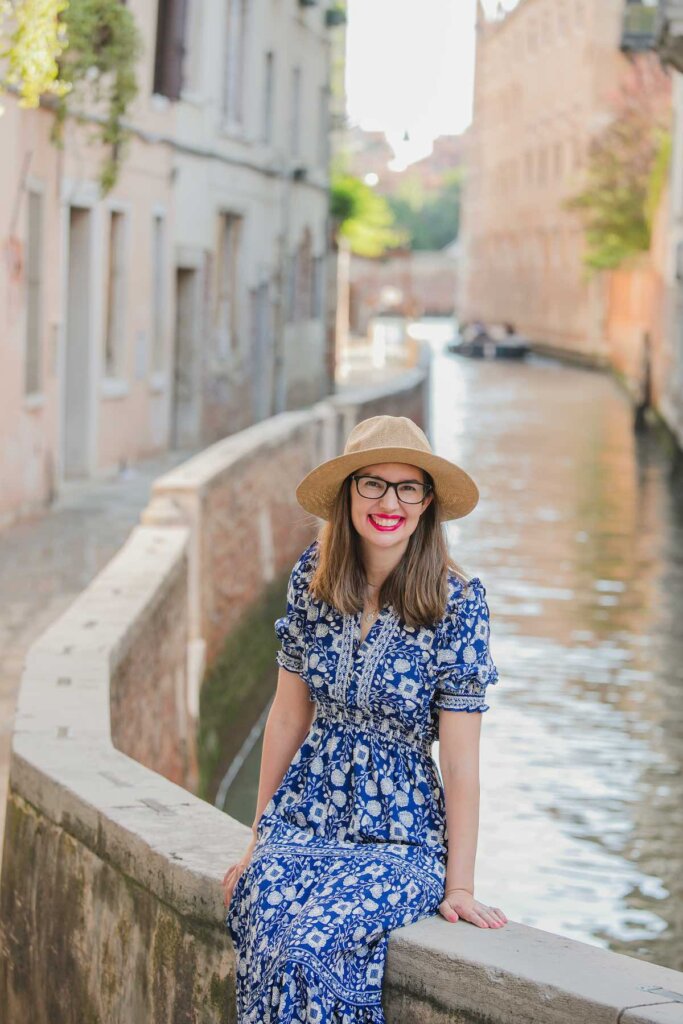 Image of a woman wearing a hat and a blue dress near a canal in Venice, Italy